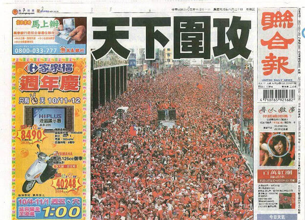 Front page of a newspaper showing a massive crowd of red-clad protesters filling a city street under bold Chinese headlines.