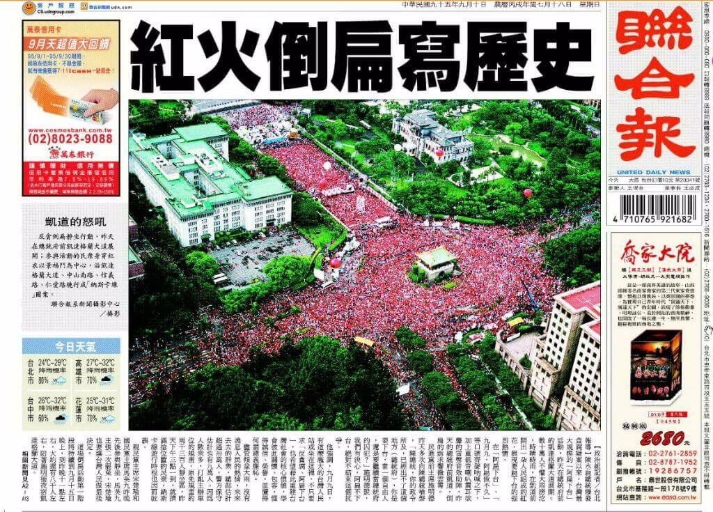 Aerial view of a large red-clad crowd filling a campus courtyard and surrounding lawns during a protest or gathering, with buildings at the edges and a central plaza.