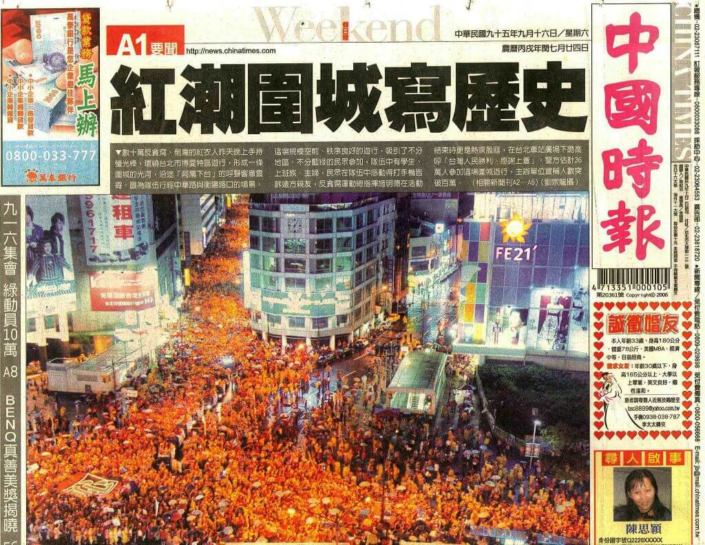 Front page of a Chinese newspaper showing a night-time street protest with a dense orange-clad crowd filling a busy city center.
